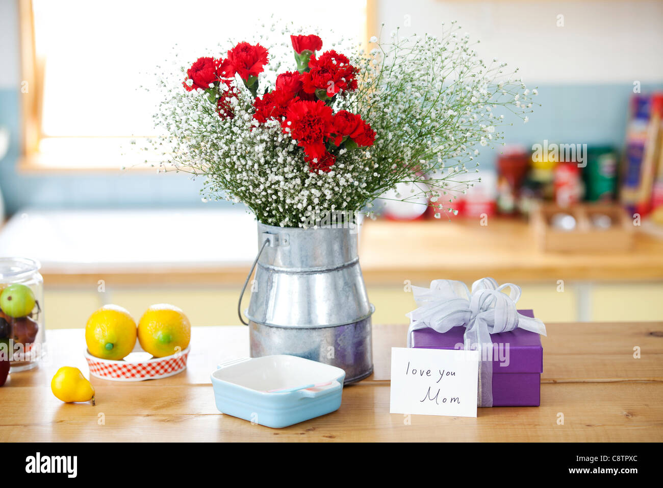 Avvolto confezione regalo e mazzo di fiori sul bancone della cucina Foto Stock