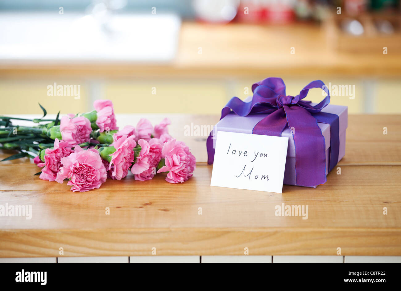 Avvolto confezione regalo e mazzo di fiori sul bancone della cucina Foto Stock