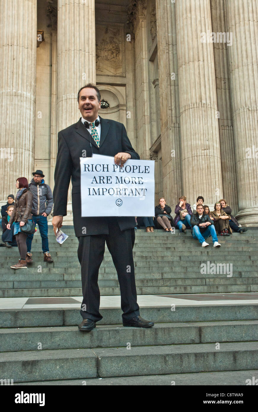 Occupare di Londra. Un uomo di mezza età vestito come un banchiere detiene una targhetta "ricchi sono più importante". Nella parte anteriore del St Pauls. Foto Stock