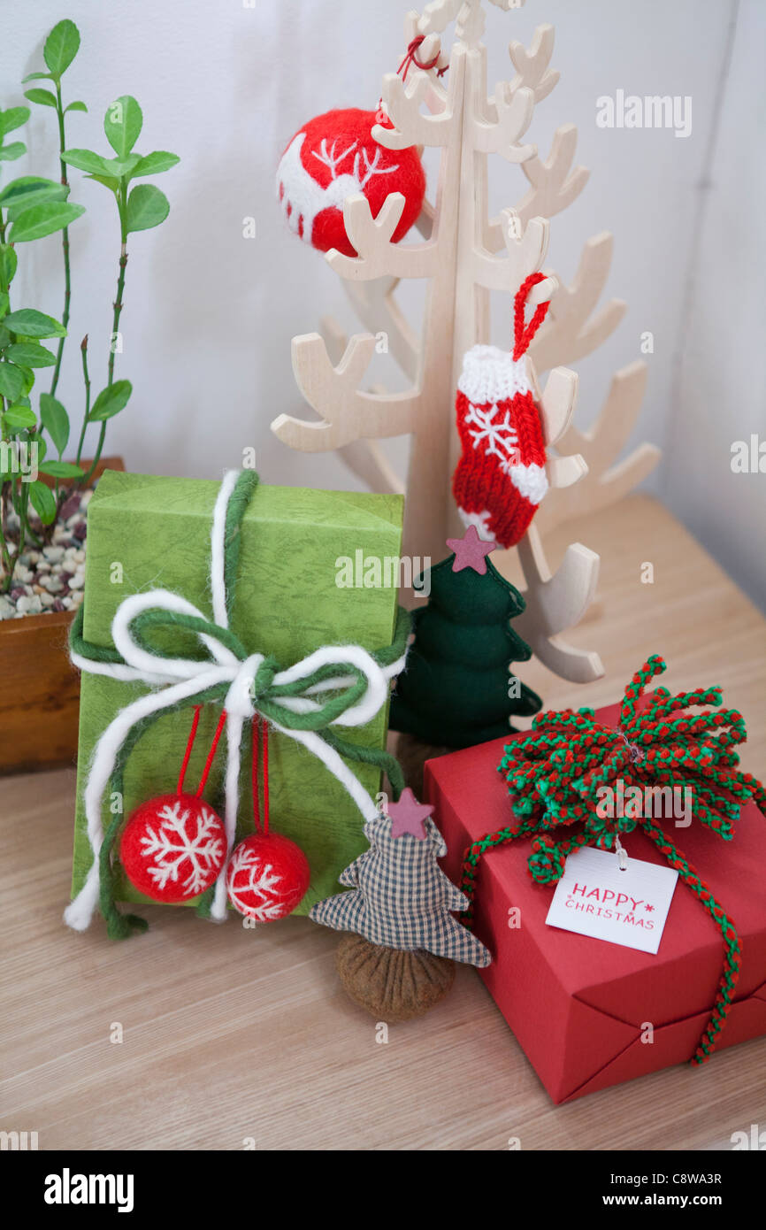 Avvolto confezioni regalo con etichetta, Ornamenti natale e vasi di piante su uno sgabello Foto Stock