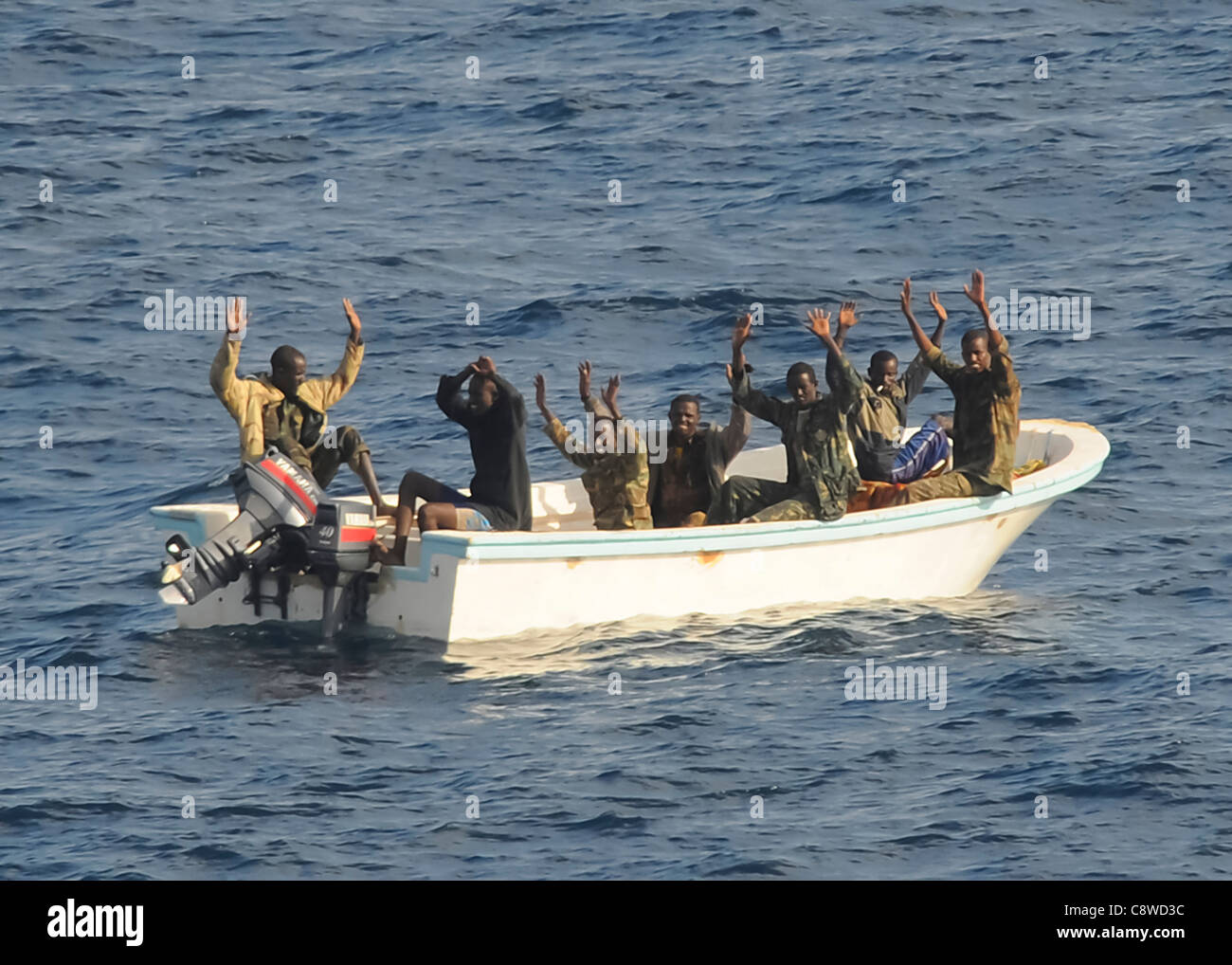 Sospetti pirati tenere le mani in aria come indicato dalle visite-missili cruiser USS Vella Gulf Foto Stock