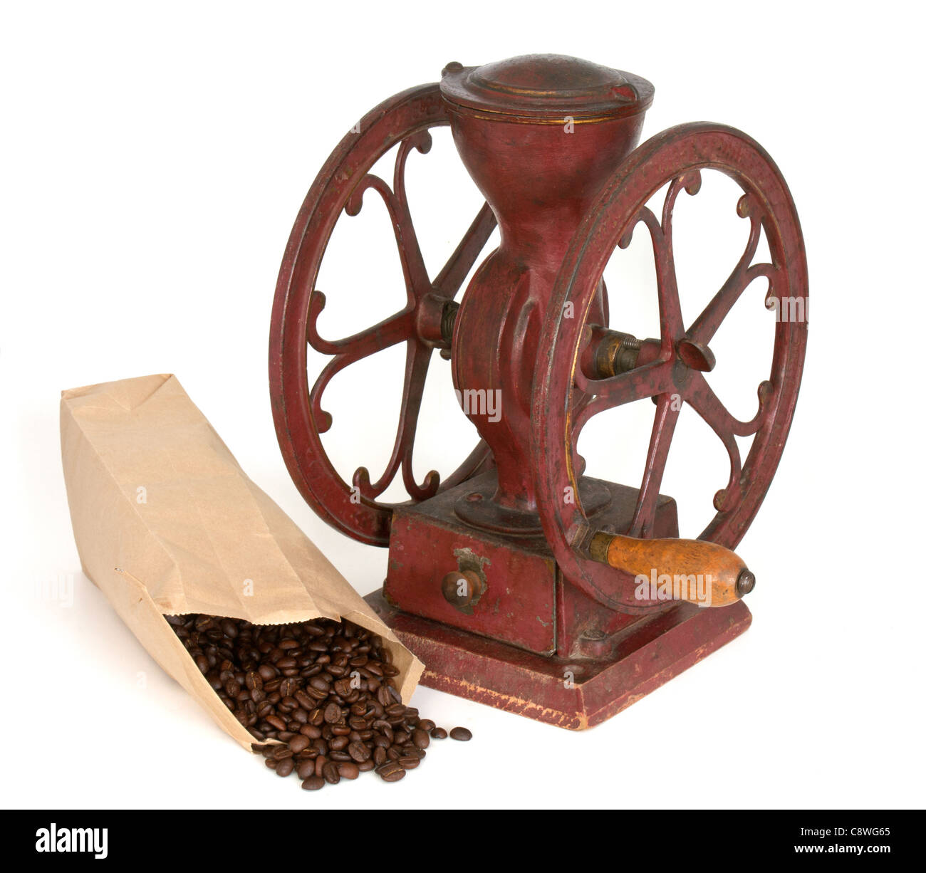 Sacco carta di aprire i chicchi di caffè nella parte anteriore della ruota di antiquariato macinino da caffè su sfondo bianco. Foto Stock