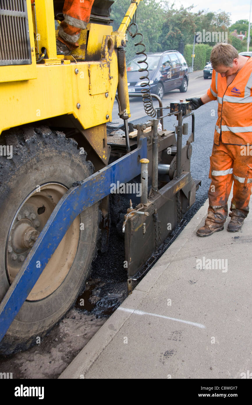 Posizionamento della guida dal marciapiede di asfalto macchina di stendimento che è la posa di un nuovo manto stradale. Foto Stock