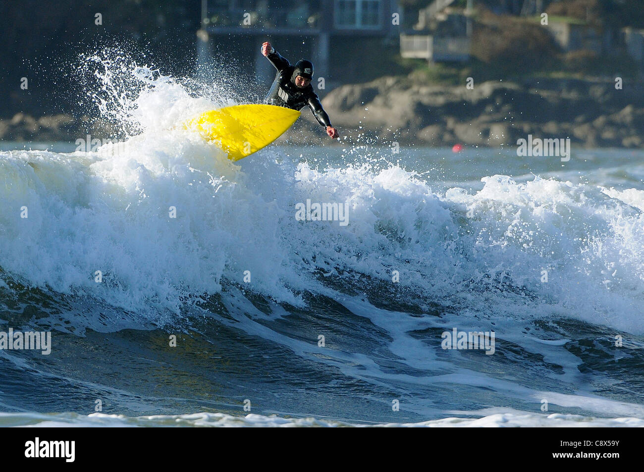 Un surfista cavalca un ondata off Bantham beach nel Devon durante il mese di novembre. Foto Stock