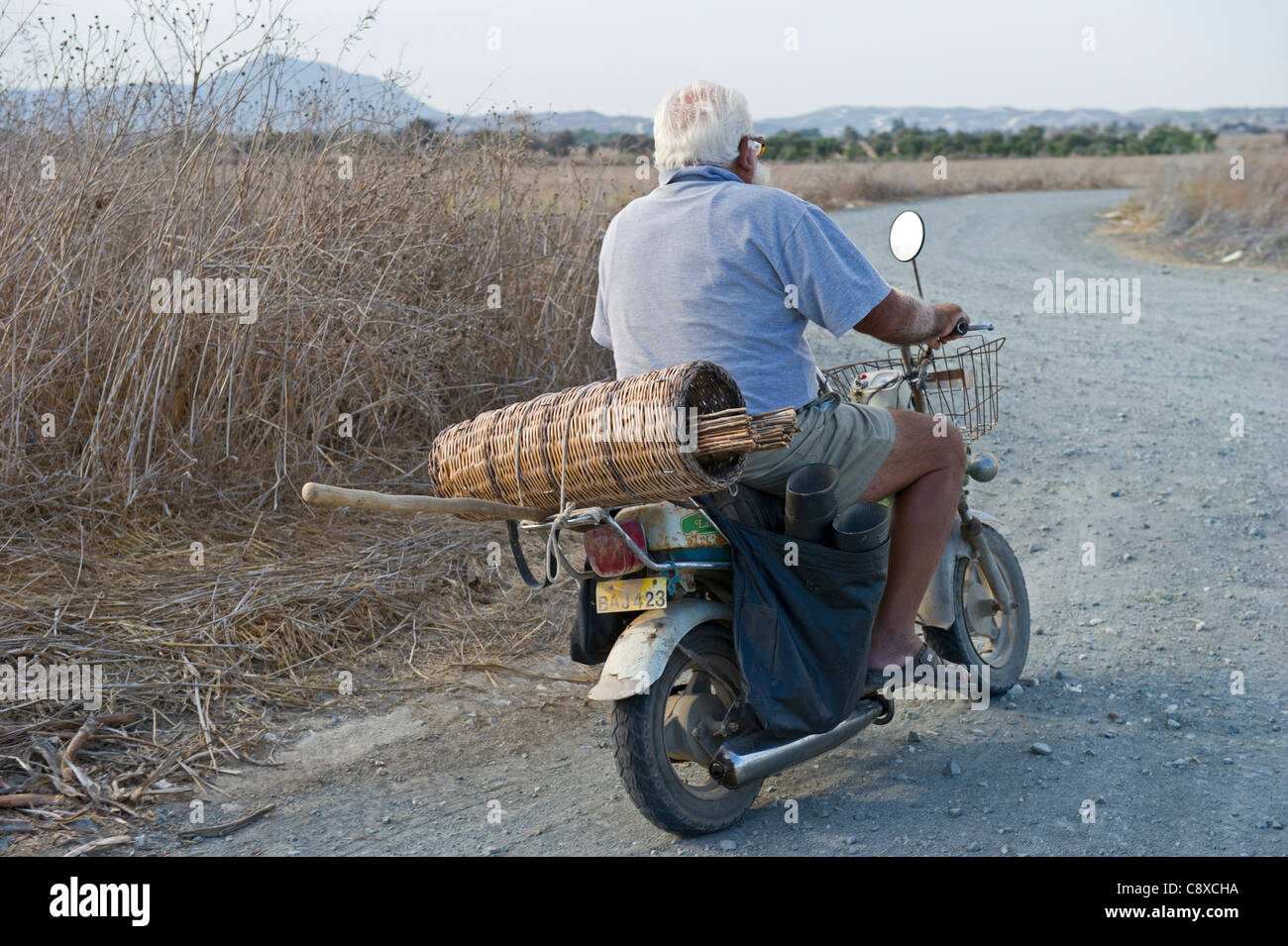 Illegale cacciatore di animali da pelliccia con limesticks sul retro del motociclo andando a Orchard per impostare fino a Cipro autunno Foto Stock