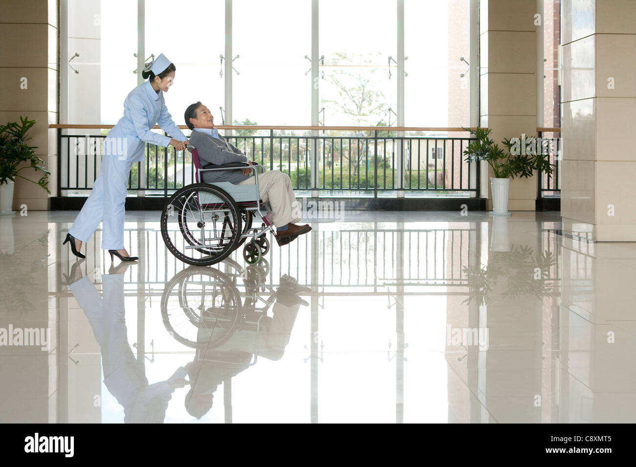 Infermiere Senior spinge l'uomo in una sedia a rotelle Foto Stock