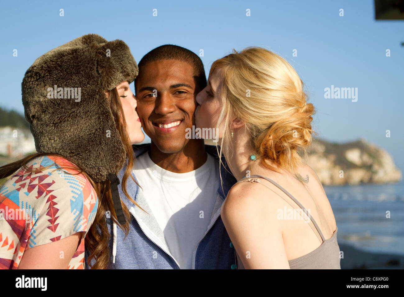 Due ragazze baciando un giovane di guancia. Foto Stock