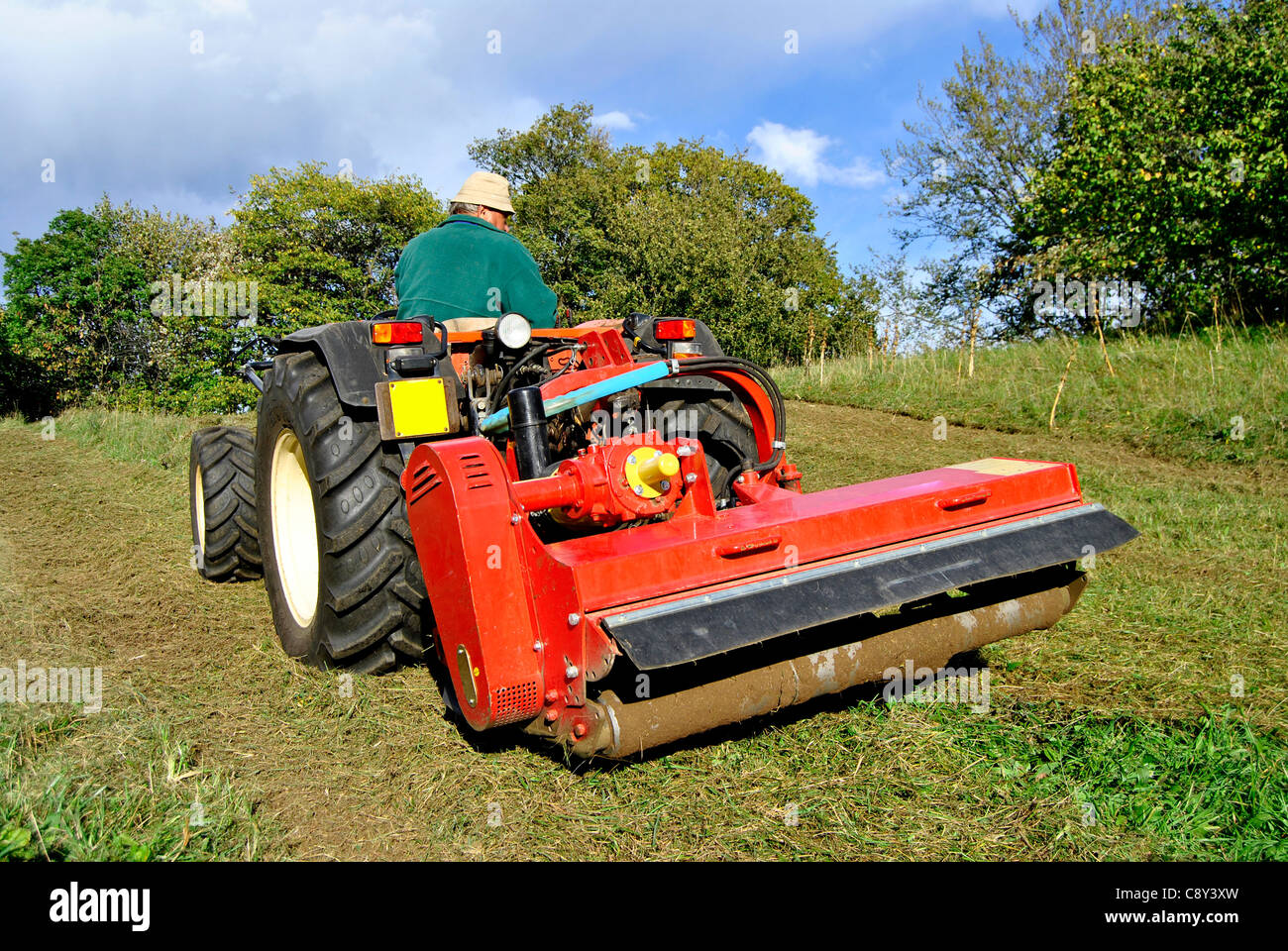 Piccola fattoria trattore hogging bush su un campo di erba in Trentino Alto Adige. Italia Foto Stock