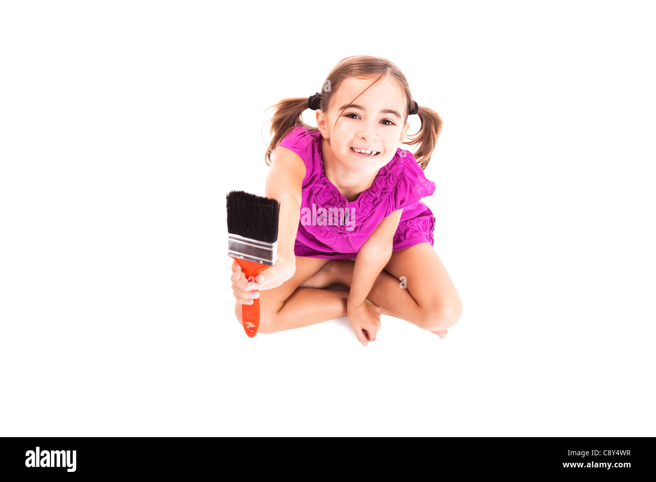 Vista dall'alto di un felice ragazza seduta sul pavimento tenendo un pennello Foto Stock
