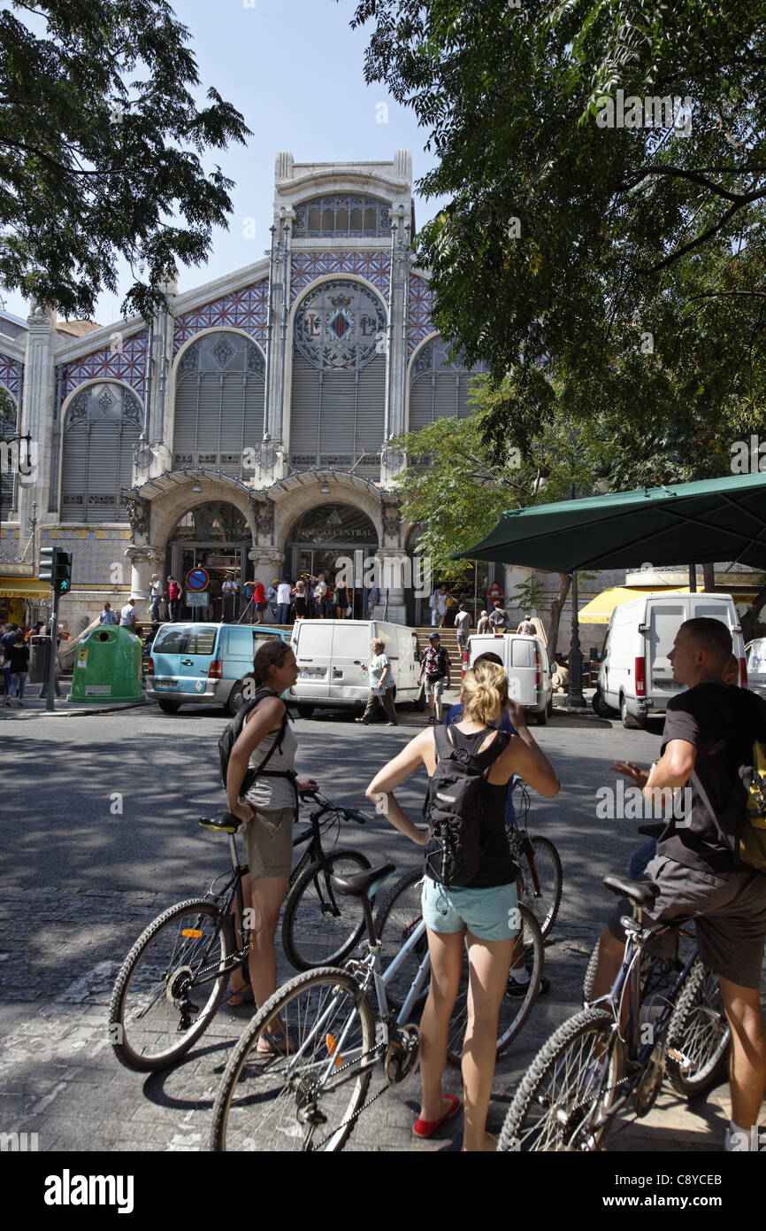 Un gruppo di giovani con le biciclette di fronte Central Market Hall , il Mercado Central, Valencia, Spagna Foto Stock