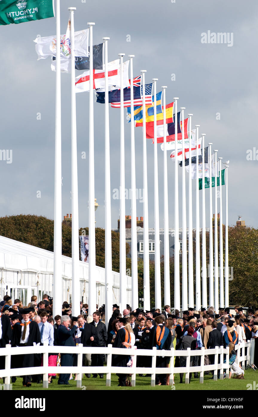 Poli di bandiera che mostra le bandiere provenienti da diversi paesi sul giorno di graduazione a Plymouth University. Persone che indossano abiti accademico. Foto Stock