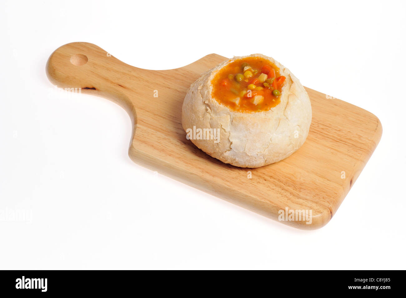 Zuppa di verdure in una boule ciotola di pane sul taglio del legno di bordo su sfondo bianco Foto Stock