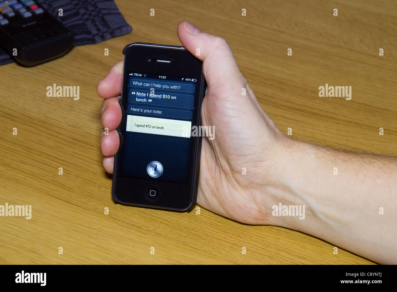 Utilizzando Siri personal assistant applicazione su un iPhone 4S utilizzando Controllo vocale per effettuare una nota che il pranzo al costo di $ 10. Foto Stock
