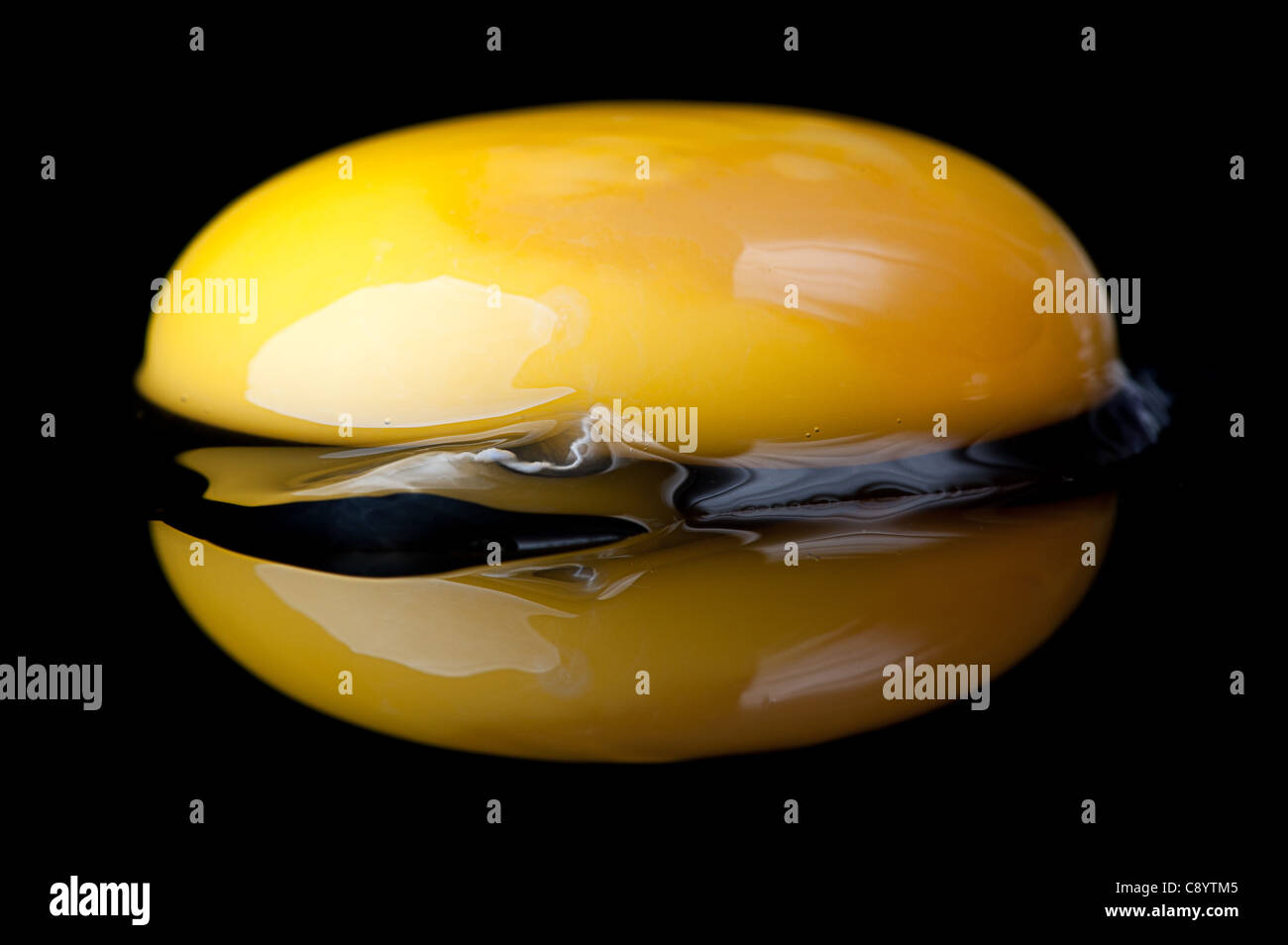 Uovo crudo e tuorlo d'uovo e la sua riflessione su un nero superficie riflettente . Foto Stock