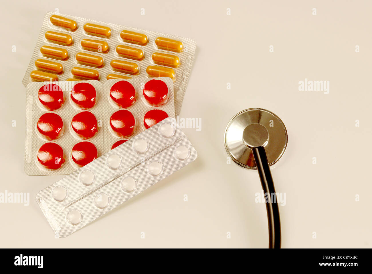 Pillole colorate e uno stetoscopio su un tavolo Foto Stock