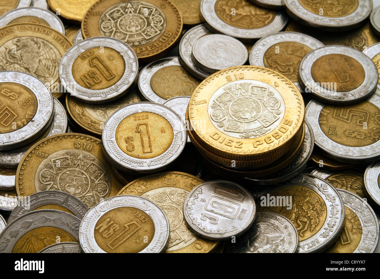Un moderno dieci pesos messicani coin impilati su un mucchio di altri moderni Peso messicano dollaro e cent. Foto Stock
