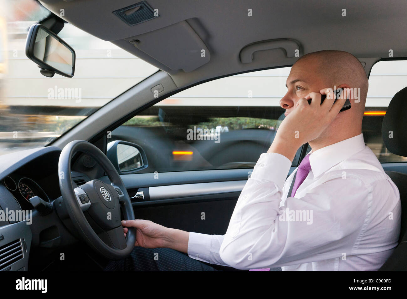 Uomo che utilizza il telefono cellulare durante la guida di auto in autostrada Foto Stock