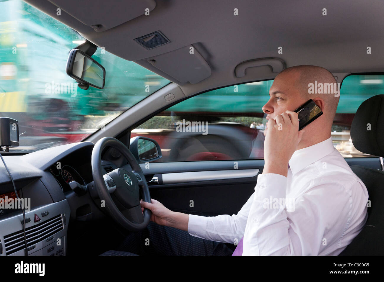Uomo che utilizza il telefono cellulare durante la guida di auto in autostrada Foto Stock
