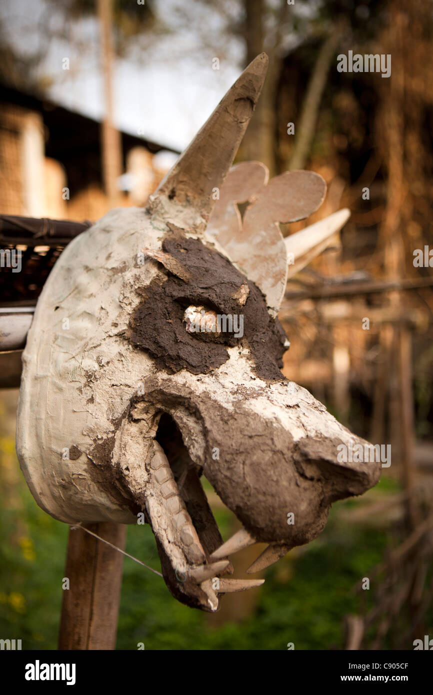 India, Assam, Majuli Island, artigianato, la produzione di maschere, officina, lupo maschera con volto modellato in argilla essiccazione su palo da recinzione Foto Stock
