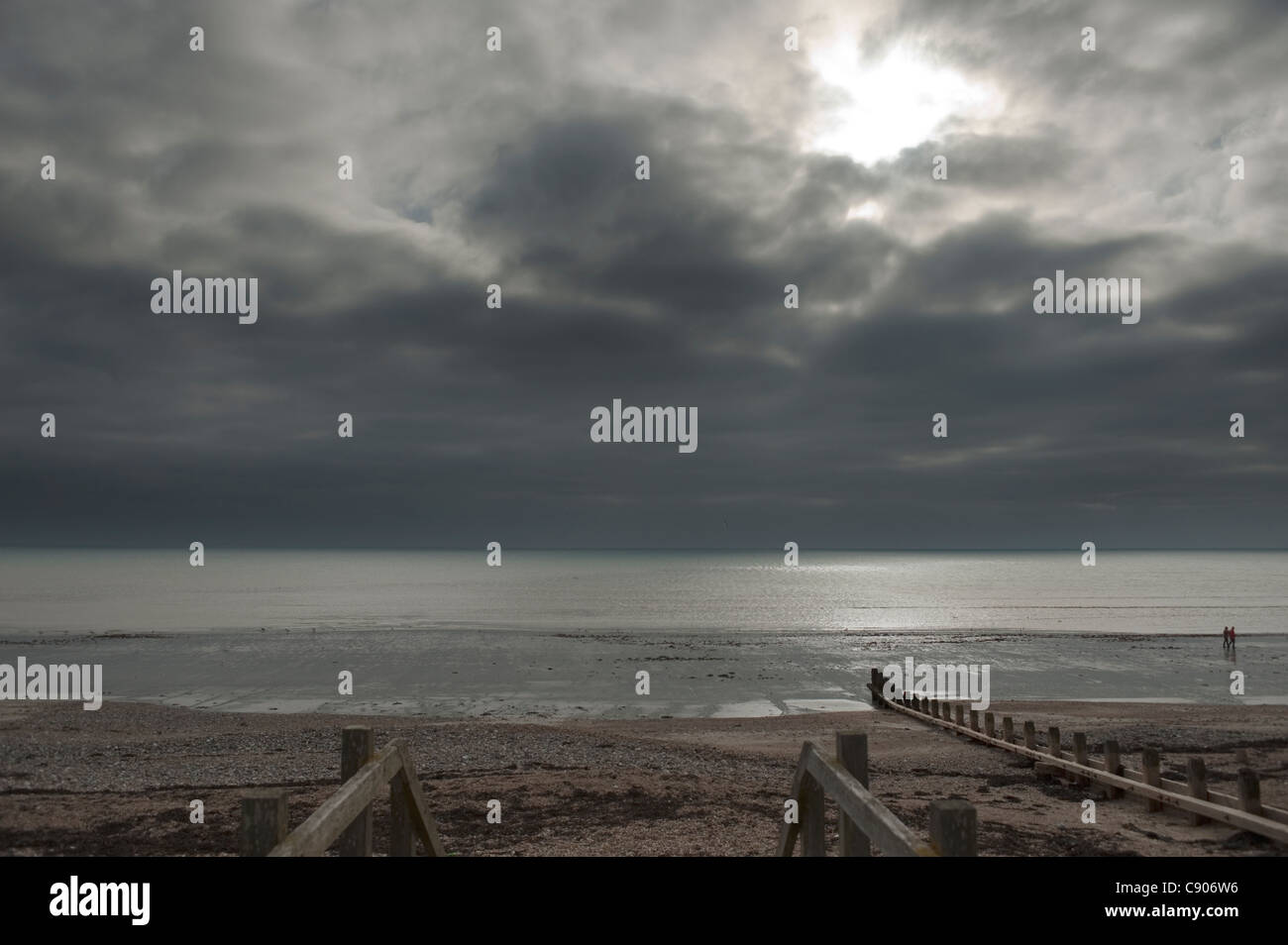 Il canale in inglese da Worthing Beach con un grigio cielo meditabondo nel tardo autunno con due figure a piedi Foto Stock