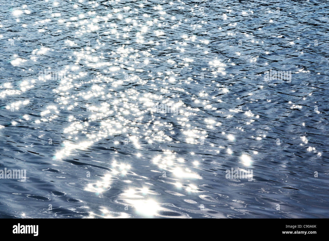 Sun raggi riflessi nell'acqua scura Foto Stock