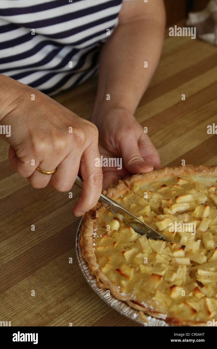 Donna di taglio in casa per affettare la torta di mele Foto Stock