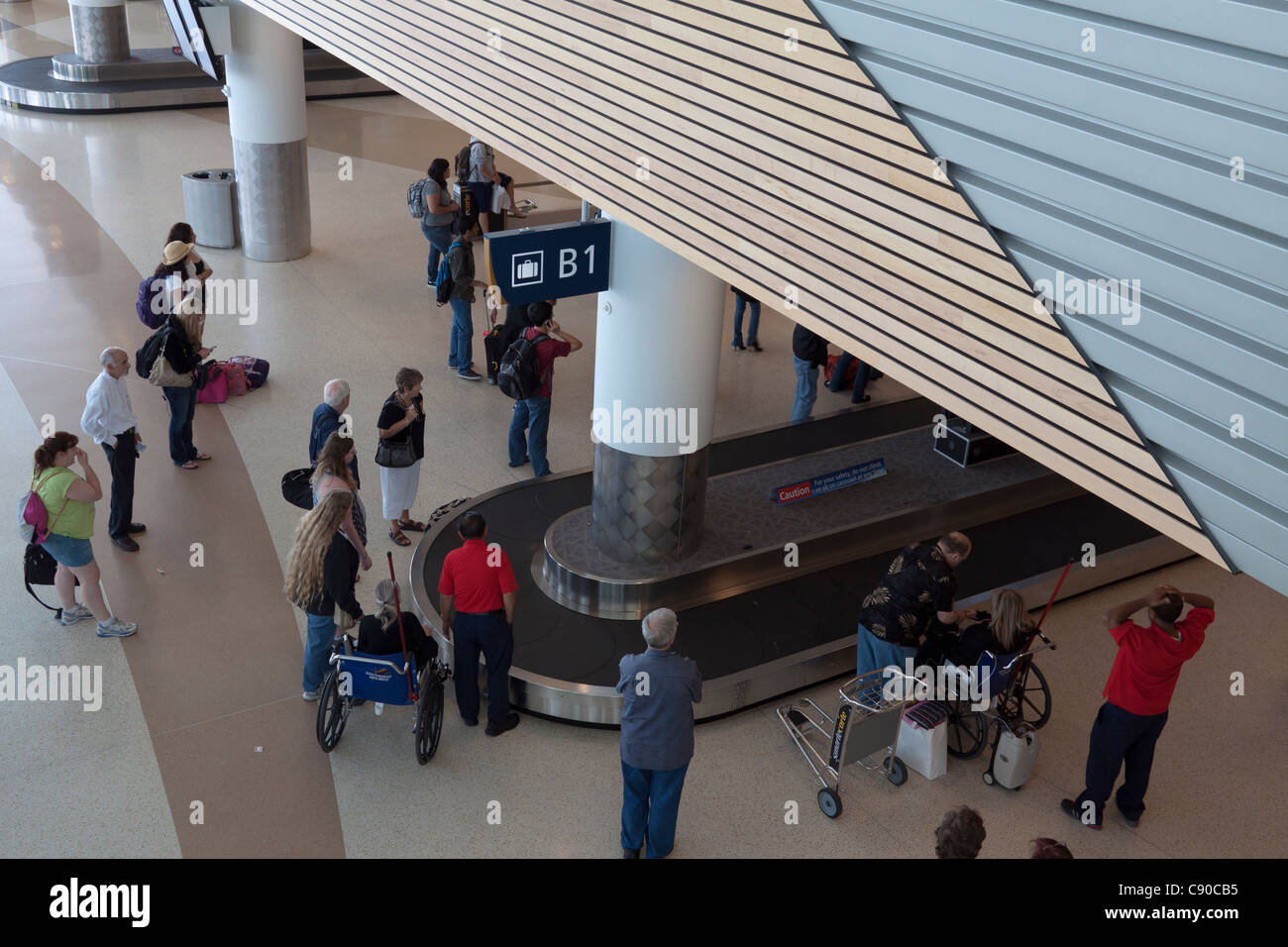 Persone in attesa per i bagagli per arrivare sul reclamo bagagli convogliatore all aeroporto di San Jose in California Foto Stock