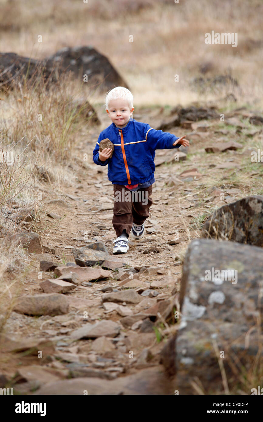 Ragazzo giovane a piedi lungo un sentiero roccioso in una regione arida. Foto Stock