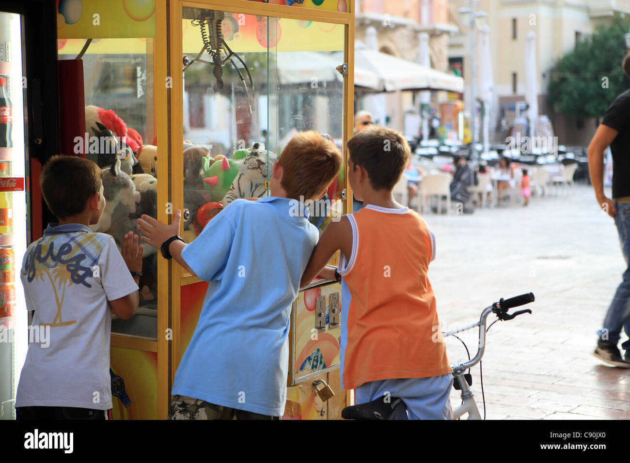 I ragazzi ad un giocattolo morbido artiglio macchina gru in Piazza Sintagmatos, Nafplion, Grecia Foto Stock