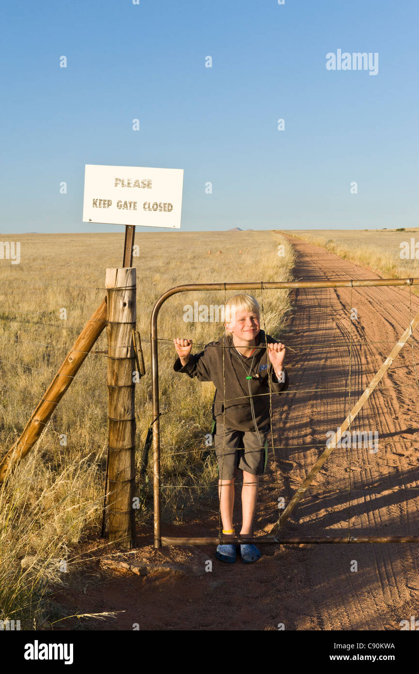 Ragazzo giocando con il cancello alla fattoria Koiimasis Tiras montagne della Namibia Foto Stock