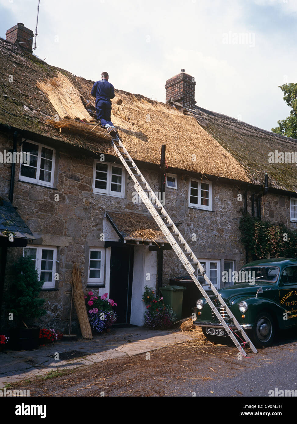 Ricoprendo di paglia è una specialità addestrato artigiani pack di paglia e di creare solide resistenti e attraenti i tetti di edifici tradizionali. Foto Stock