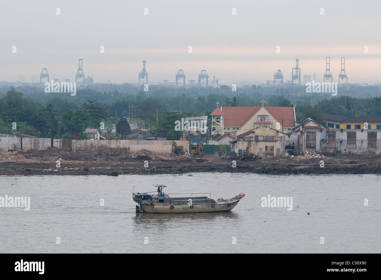 Vecchia vela chiatta giù il fiume SAIGON in Ho Chi Minh City, Vietnam con il moderno porto di gru in background. Foto Stock