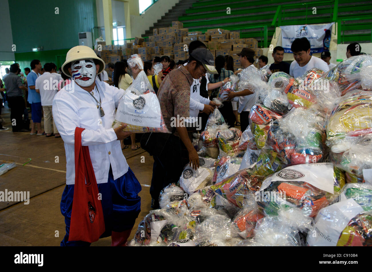 Volunteer w/ bandiera tailandese dipinto sul volto consente il caricamento del carrello di sfiato w/ donato forniture. Lo Stadio Nazionale di Bangkok, Tailandia il Lunedì, Novembre 7th, 2011. Thailandia sta vivendo la sua peggiore inondazione in più di cinquant'anni. Credito: Kraig Lieb Foto Stock