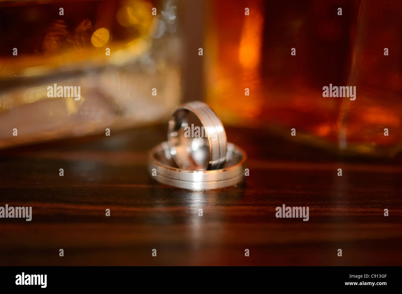 Triste visione del futuro. Due anelli di nozze con whisky in background. Foto Stock