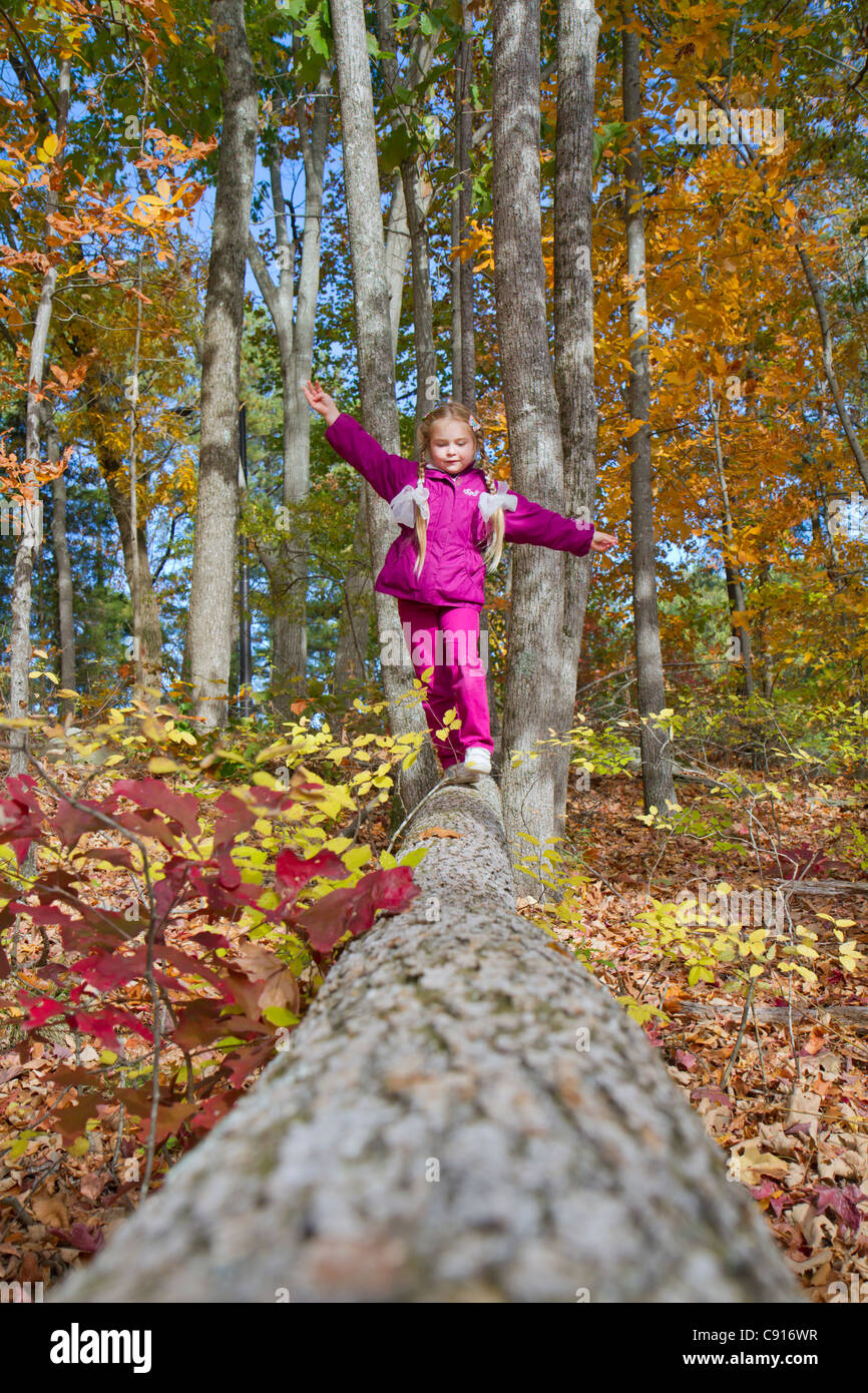 Una bambina di 7 anni che cammina sul bosco caduto nella foresta autunnale, Stone Mountain, Georgia, USA. Foto Stock