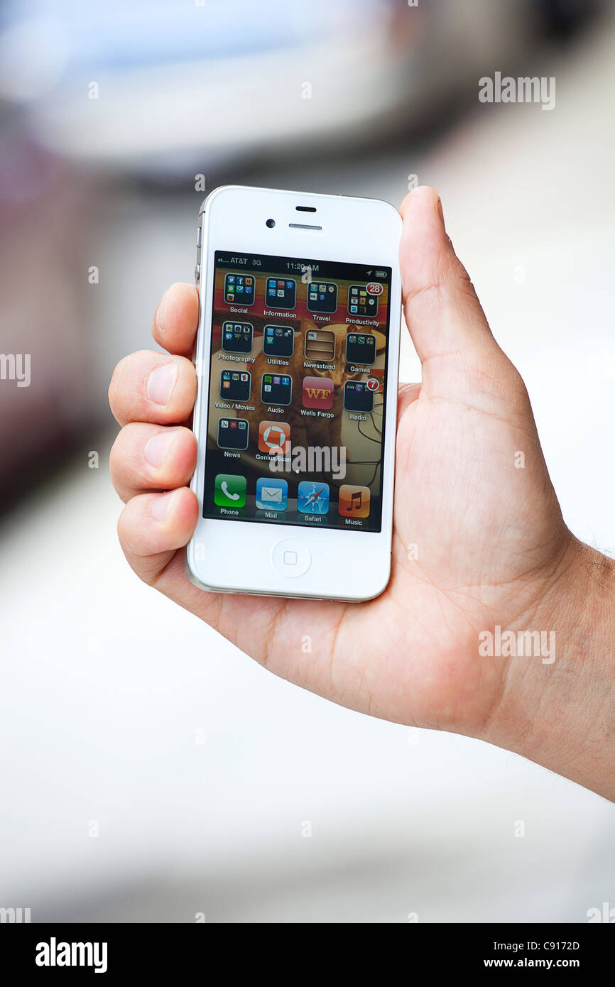 Un bianco Mac Apple iPhone 4S essendo tenuto a mostrare le app sulla schermata home. Foto Stock