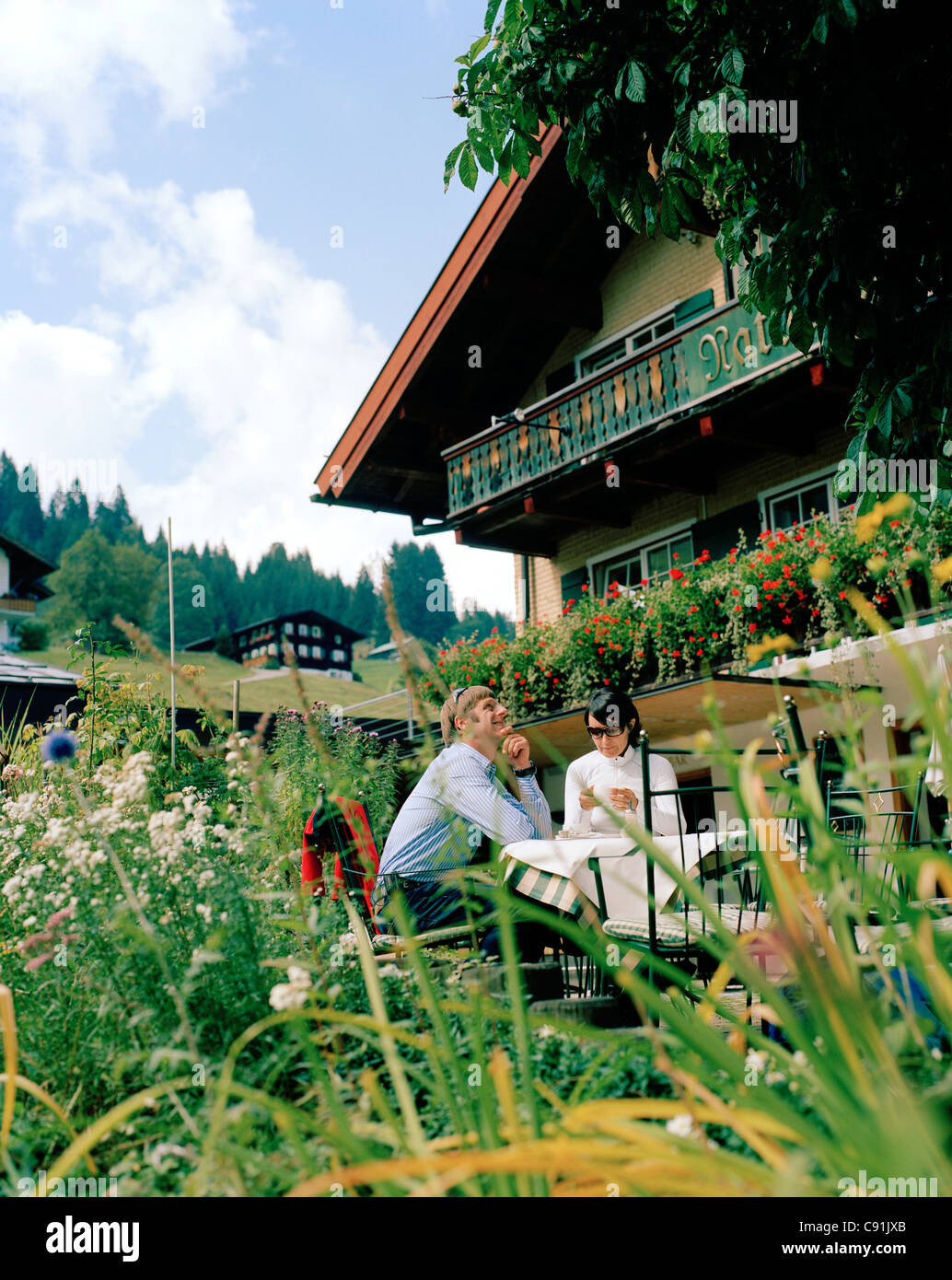 Giovane seduto nel giardino di organico albergo Chesa Valisa, Hirschegg, Kleinwalsertal, Stiria, Austria Foto Stock