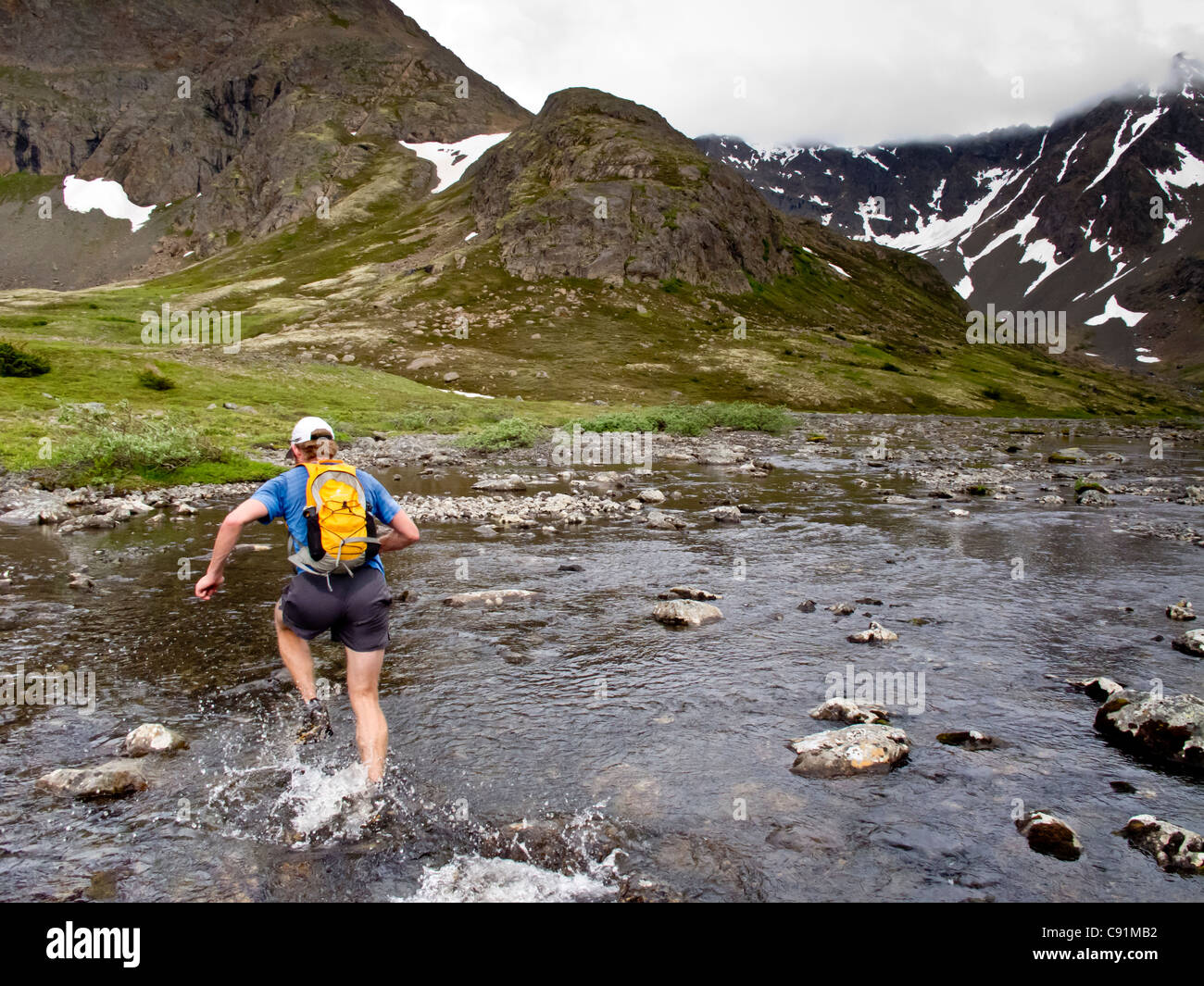 Trail runner schizzi attraverso la forcella centrale Campbell Creek mentre si esegue mount Elliot a Wolverine Peak al punto arrugginito, Alaska Foto Stock