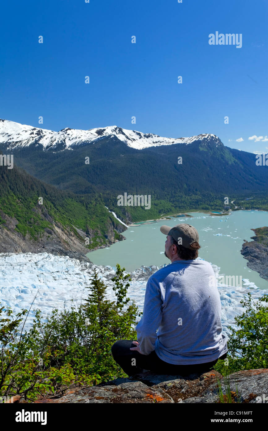 Un maschio di escursionista guardando verso il basso sulla Mendenhall Glacier e Mendenhall Lago da West glacier Trail, Juneau, a sud-est di Alaska, estate Foto Stock