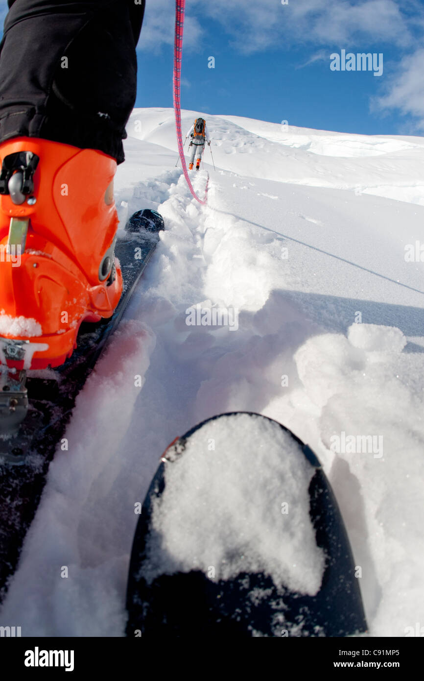 Basso angolo vista di cordata sciatori lasciando il campo sul ghiacciaio triumvirato a salire il monte Torbert, Tordrillo Mountains, Alaska Foto Stock