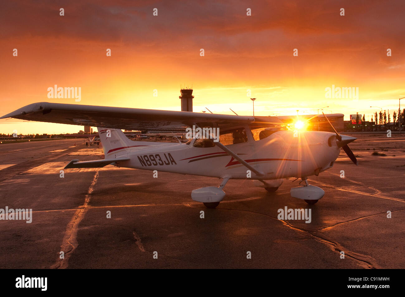 Il sole tramonta dietro un Cessna 172 a Merrill Field di Anchorage, centromeridionale Alaska, estate Foto Stock