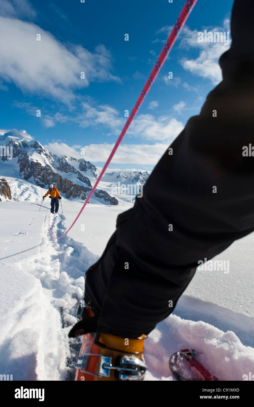 Basso angolo vista di cordata sciatori lasciando il campo sul ghiacciaio triumvirato a salire il monte Torbert, Tordrillo Mountains, Alaska Foto Stock