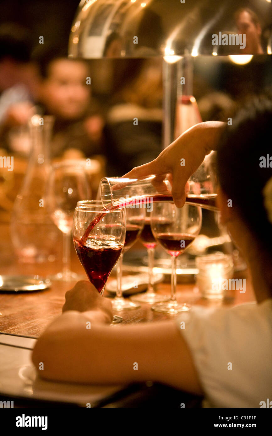 La cameriera è versando il vino rosso in vetro. Foto Stock