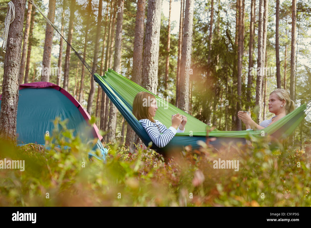 Le donne nella rilassante amaca in campeggio Foto Stock