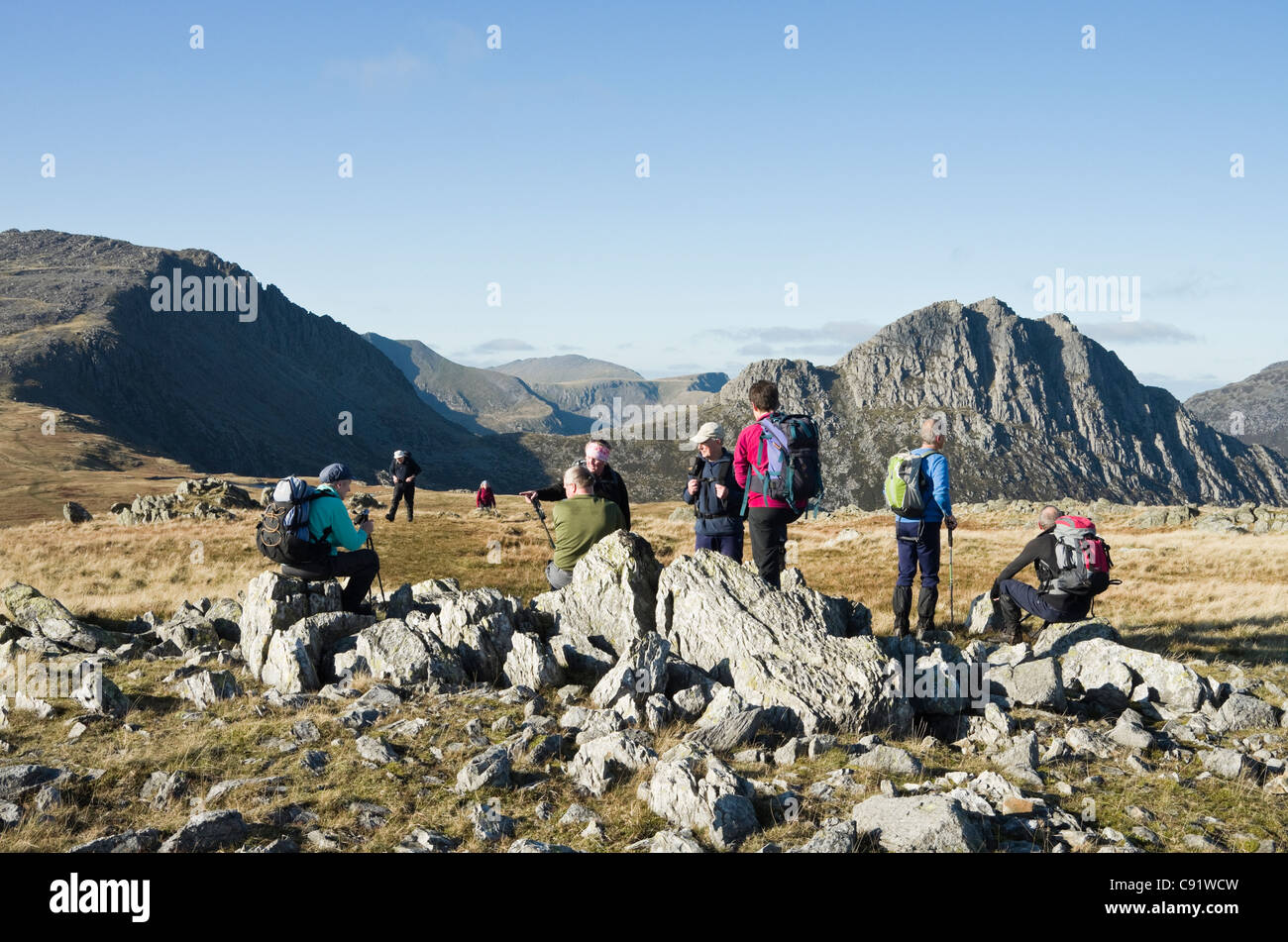 Gruppo di escursionisti in appoggio sulla salita di Y Foel Goch con Tryfan e Glyder Fach ispido ridge in Snowdonia National Park Regno Unito Foto Stock