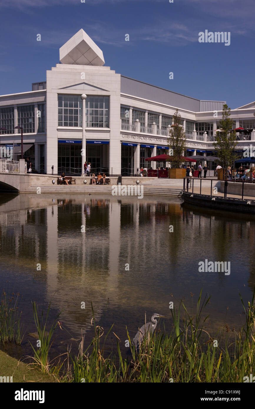 Airone di pesca in lago da outdoor Food plaza e architettura moderna a Bluewater Shopping Centre, Penzance, Kent, England, Regno Unito Foto Stock