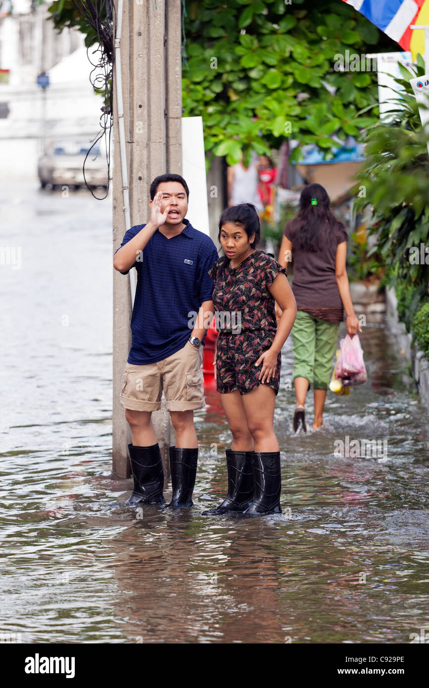 Persone di indossare stivali di gomma in acqua di inondazione in Bangkok city centre, Thailandia Foto Stock