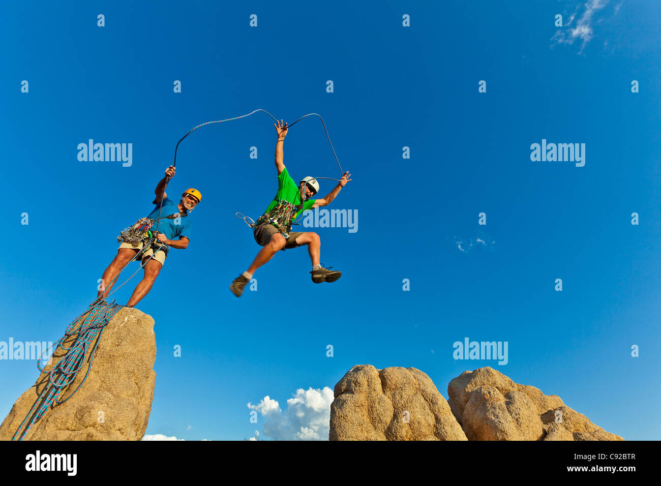 Team di scalatori nella lotta per il vertice di un pinnacolo di roccia dopo una impegnativa salita. Foto Stock