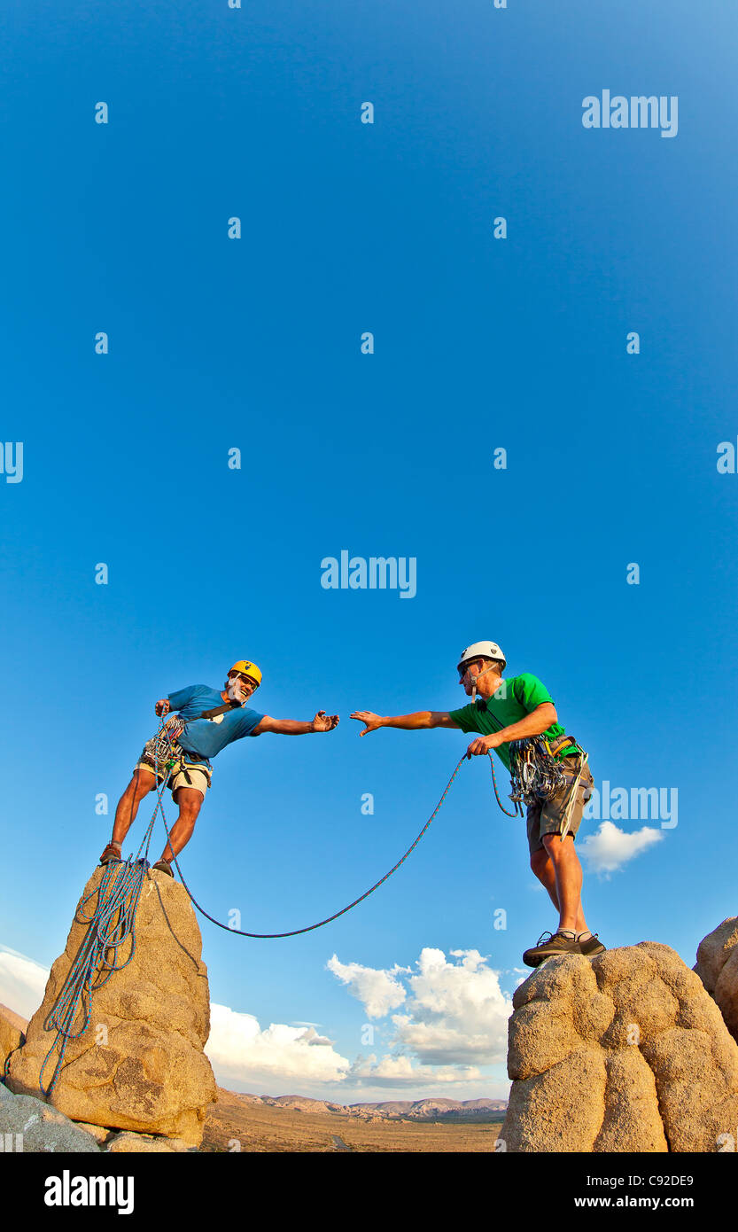 Team di scalatori nella lotta per il vertice di un pinnacolo di roccia dopo una impegnativa salita. Foto Stock