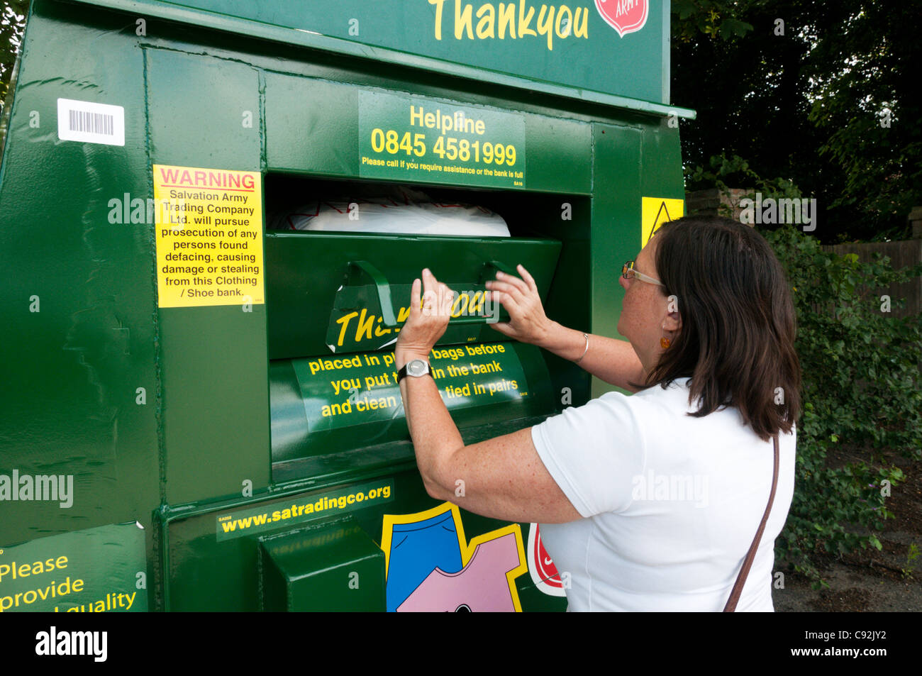 Una donna mette un sacco di capi di abbigliamento in un Esercito della salvezza la carità punto di raccolta per indumenti indesiderati & Scarpe. Foto Stock